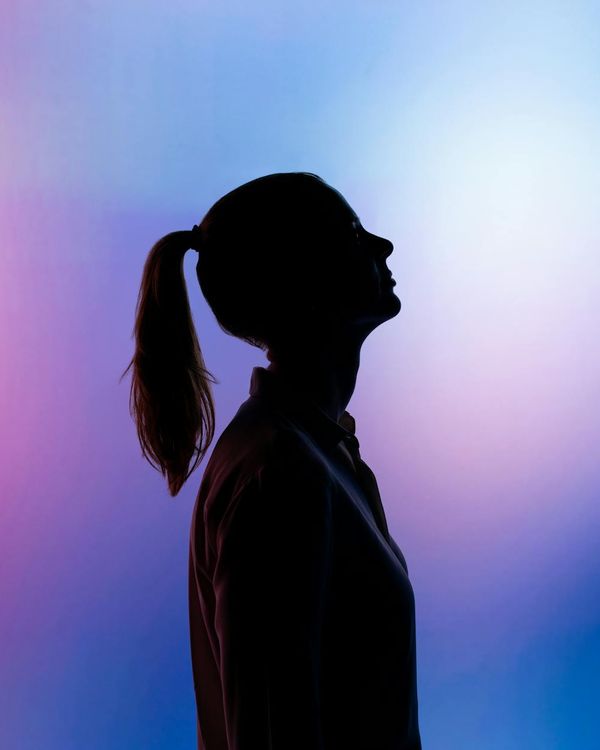Silhouette of a person in a strong yoga warrior pose against a light background.