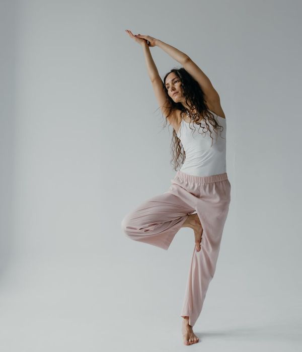 Woman in a flowing yoga pose in a dark, minimalist studio.